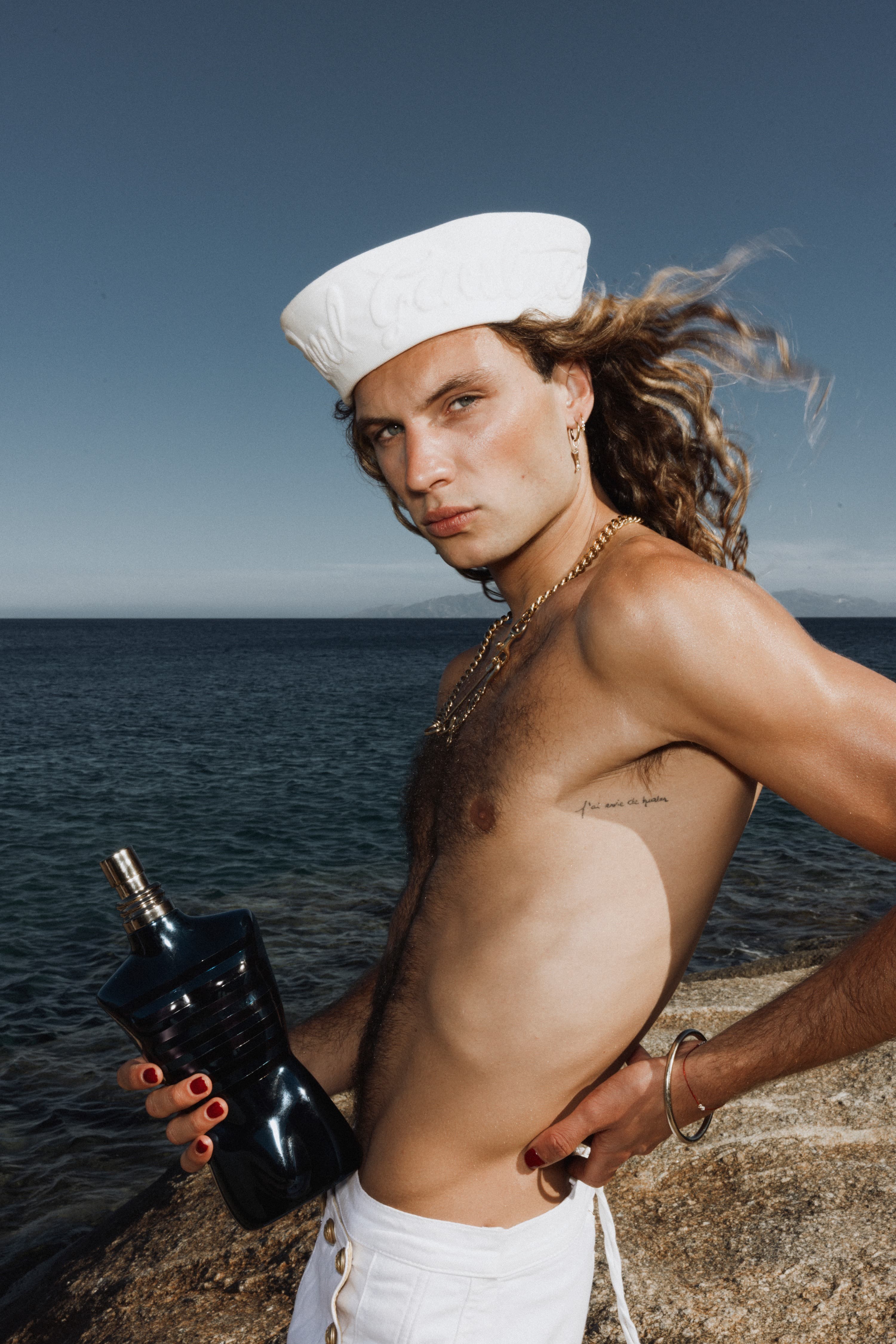 Créateur en marinière avec un flacon Le Male face à la mer