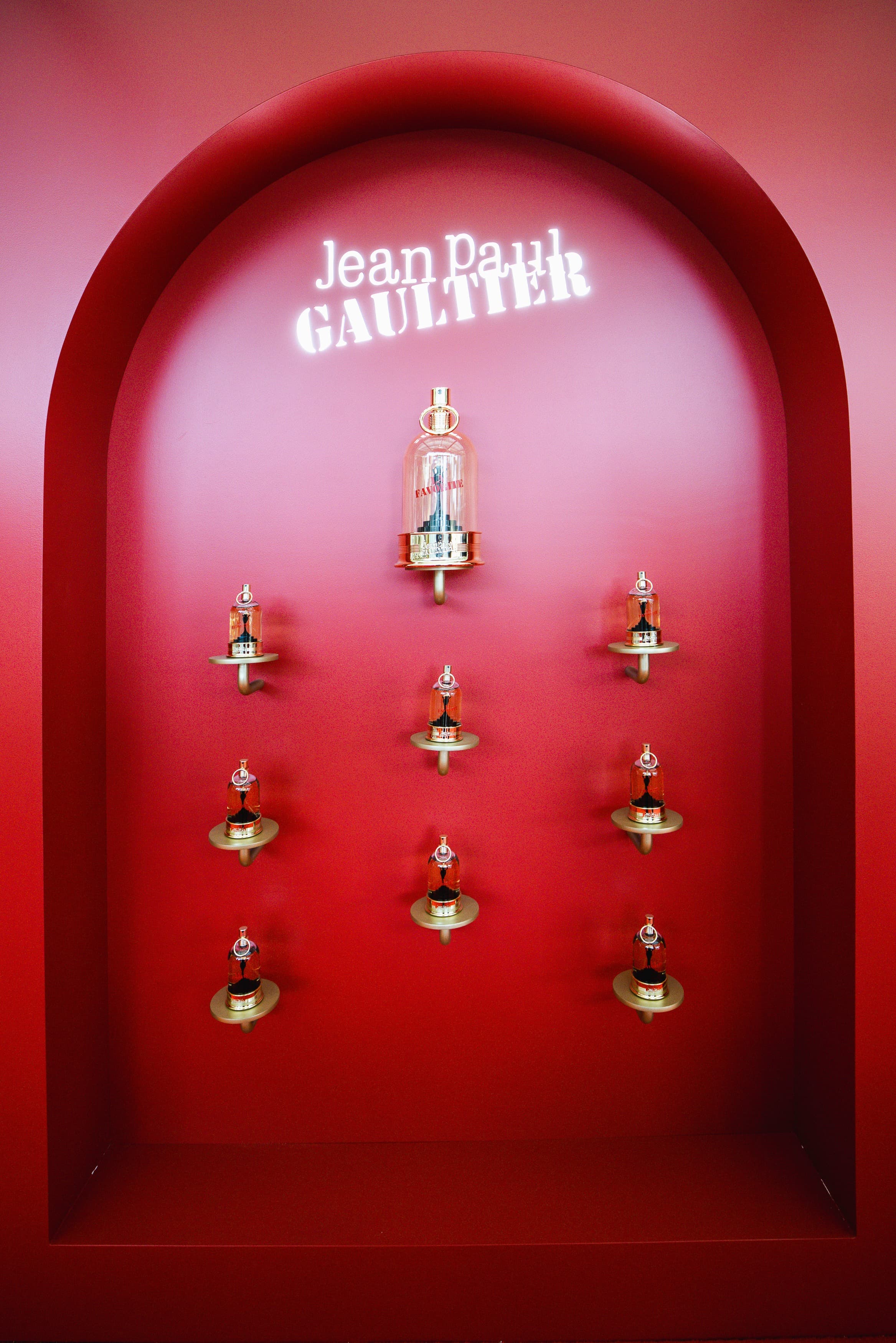 Niche rouge présentant les flacons de l'Eau de Parfum La Favorite sous le logo Jean Paul Gaultier