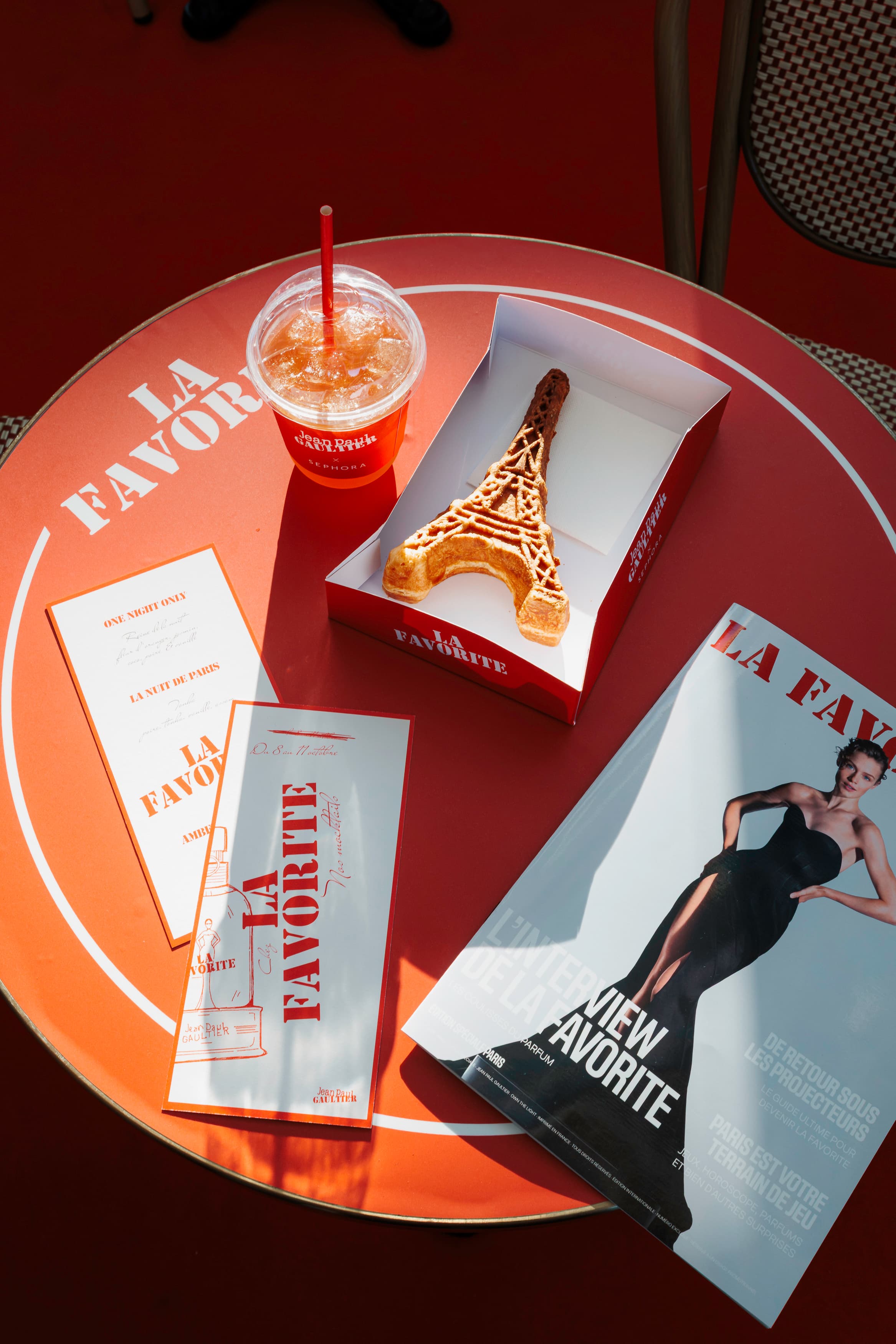 Table du café La Favorite vue du dessus : boisson, gâteau en forme de Tour Eiffel, menu et magazine Jean Paul Gaultier