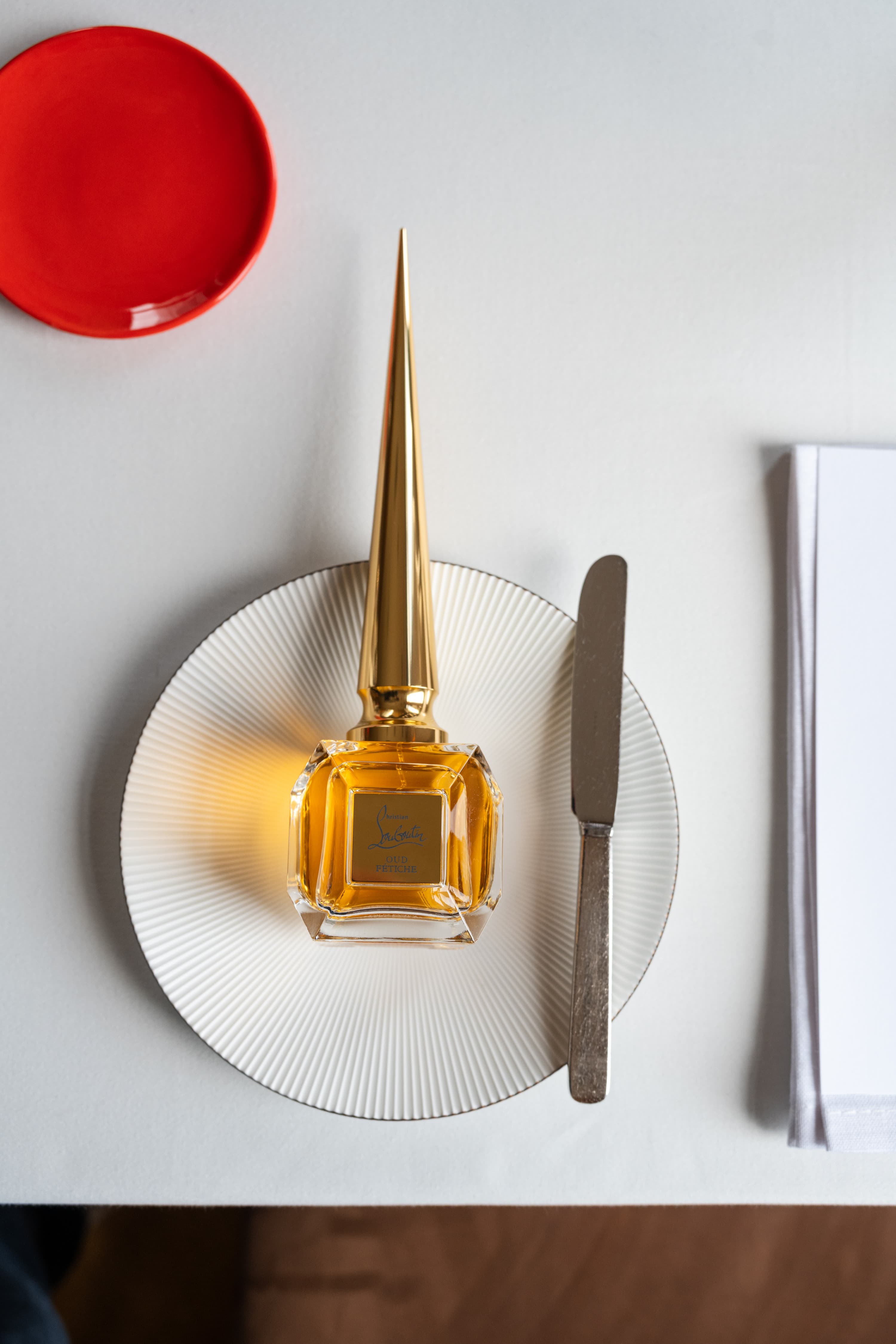 Flacon Louboutin présenté sur une assiette du dîner