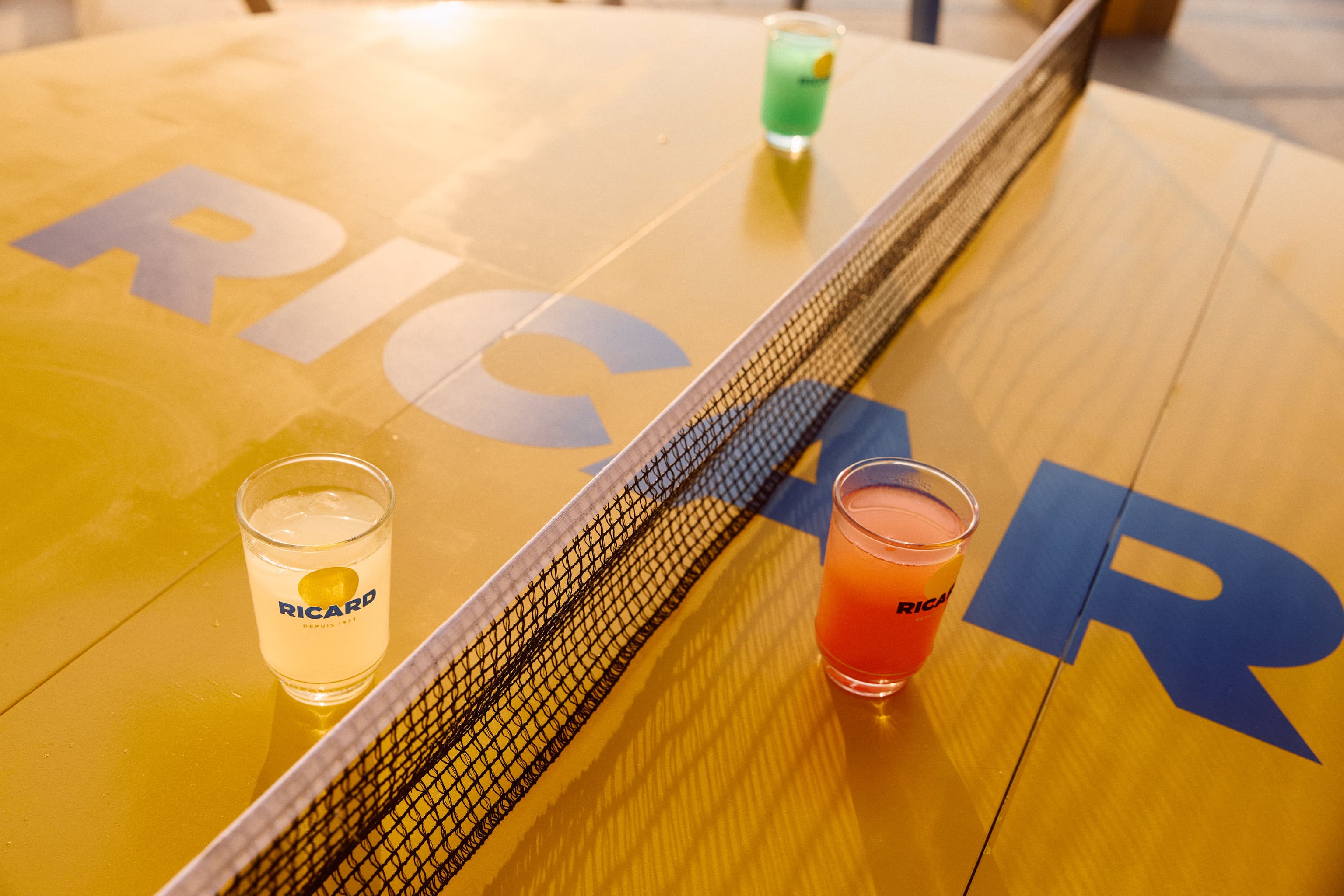 Table de ping-pong aux couleurs Ricard avec trois cocktails servis sur le plateau lors du Ricard Summer Tour 2026