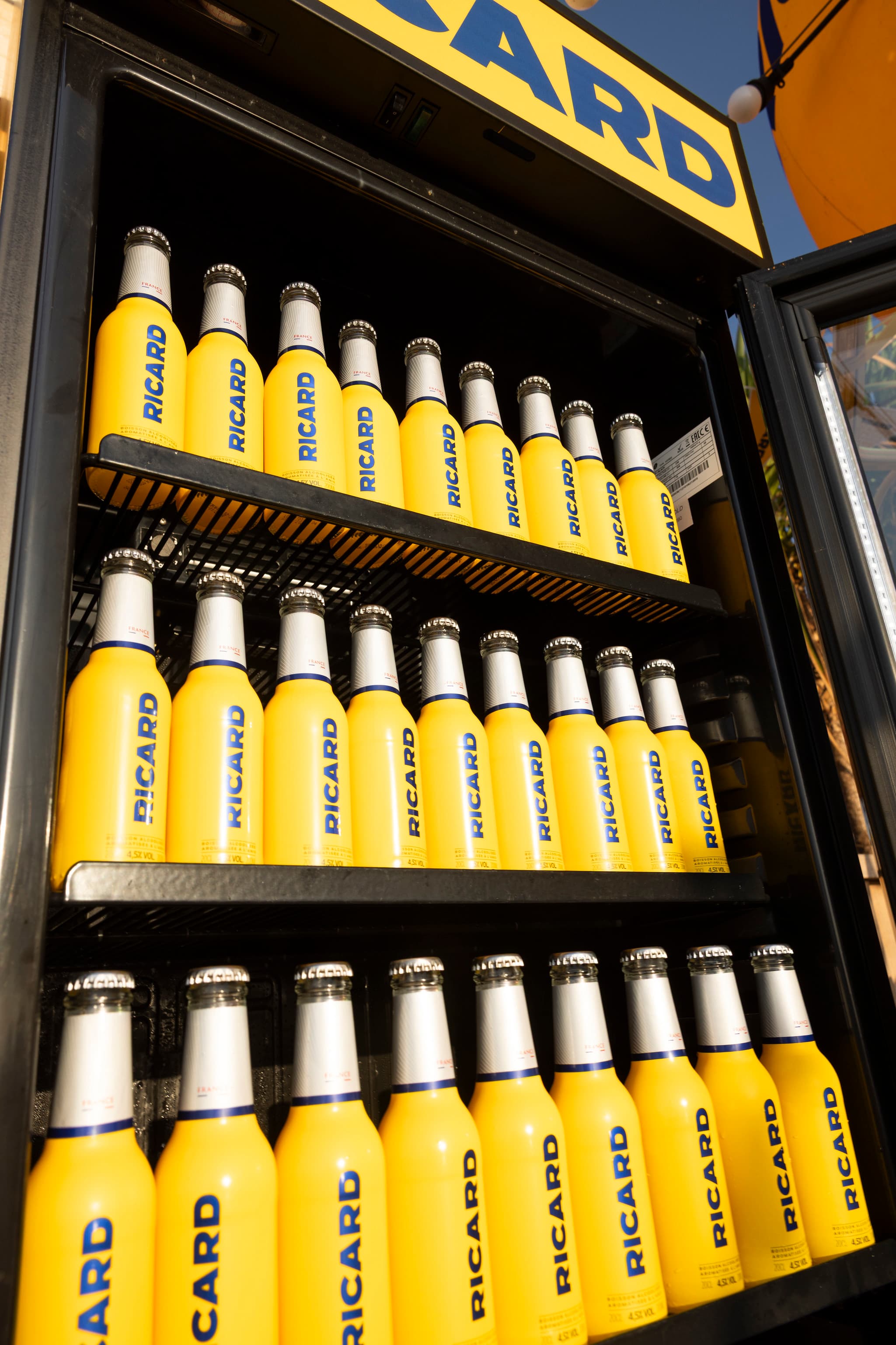 Réfrigérateur Ricard rempli de bouteilles jaunes dans un établissement partenaire de la tournée